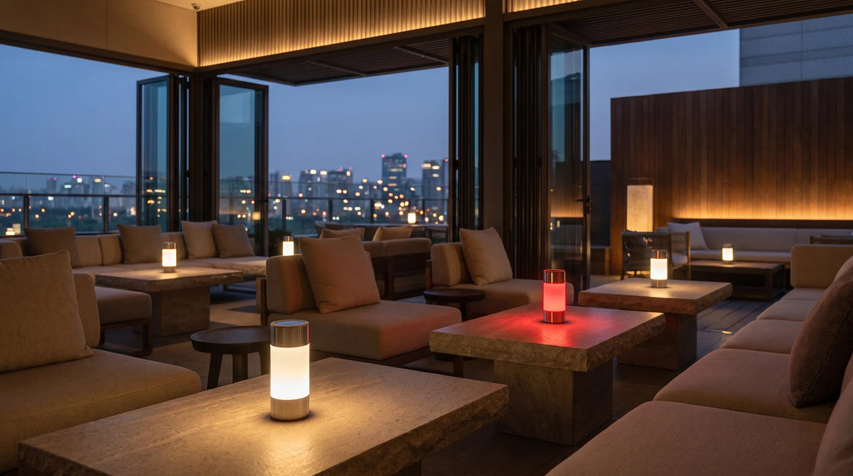 A hotel lounge terrace at dusk with Halune lamps on the tables, one glowing red